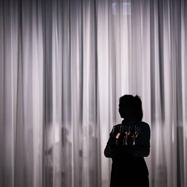 Eine Servicemitarbeiterin steht vor einem hellen Vorhang
