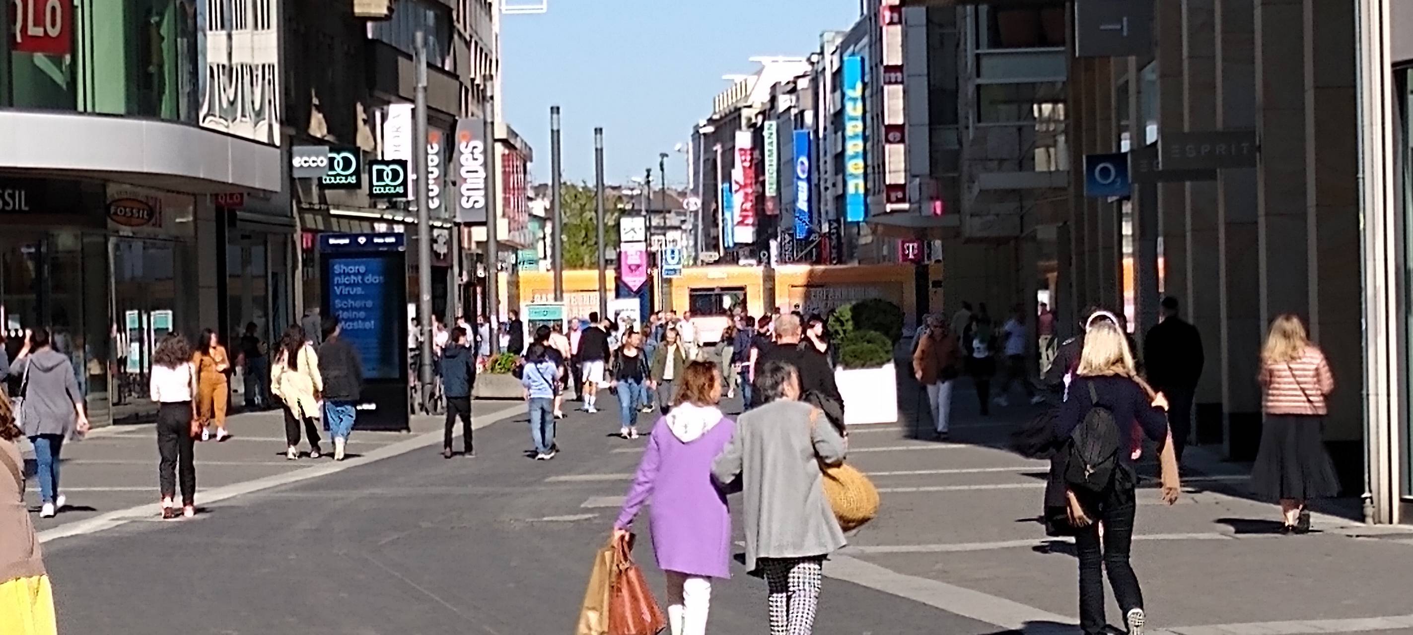 Mehrere Passanten laufen mit Einkaufsstaschen über die Schadowstraße in Düsseldorf.