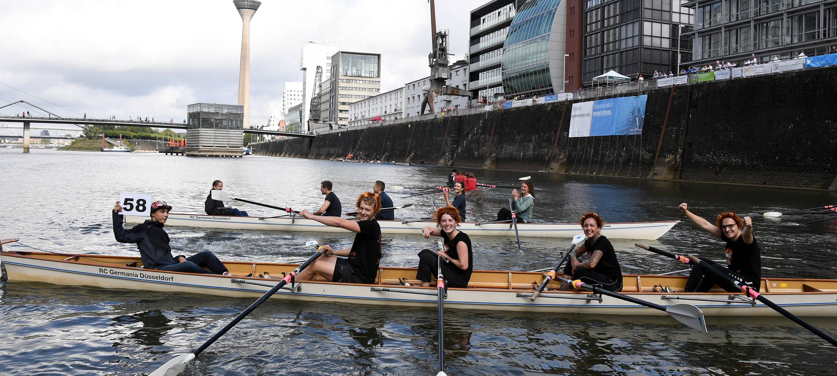 8 Menschen sitzen in zwei Ruderbooten im Medienhafen