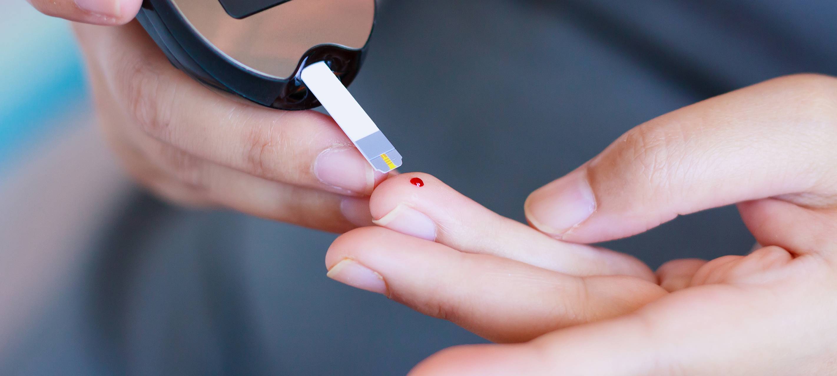 Diabetes-Test - eine Person hat sich gerade gepikst und misst den Zuckerspiegel.
