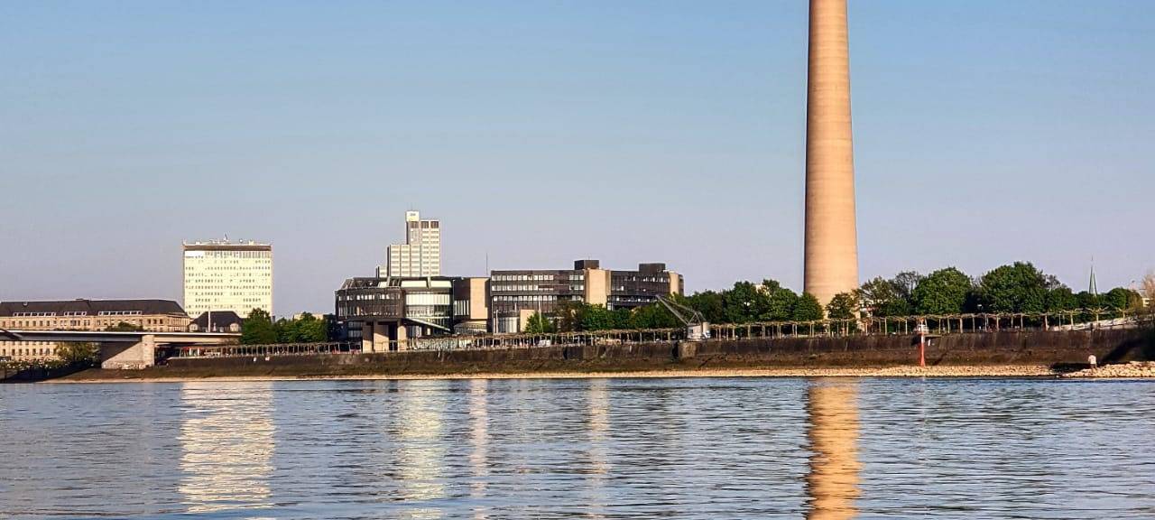 Der Rheinturm bei bestem Wetter. Er spiegelt sich sogar im Rhein.